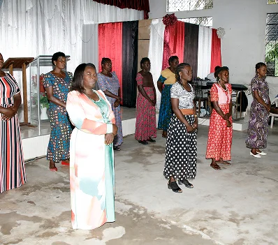 Women standing in worship inside a church hall
